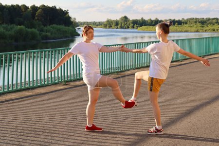 Photo for Paired family workout of daughter and mother on the river embankment - Royalty Free Image