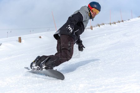 Téléchargez les photos : Jeune homme snowboard sur les pistes d'une station de ski - en image libre de droit
