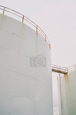 Téléchargez les photos : Basse inclinaison des réservoirs en béton blanc avec balustrades métalliques reliées par un pont sous un ciel gris - en image libre de droit