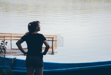 Téléchargez les photos : Femme se tient devant le bateau et filet de pêche regardant loin - en image libre de droit