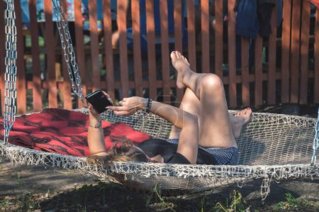 Photo for Woman with smartphone resting in round hammock - Royalty Free Image