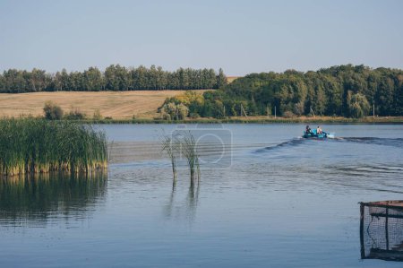 Photo for Two fishemen in motor boat sails dissecting waves on river again - Royalty Free Image