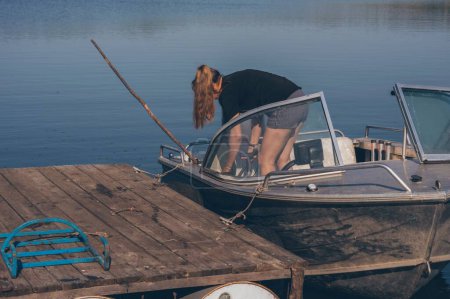 Photo for Woman bent over in motor boat on river on sunny day - Royalty Free Image