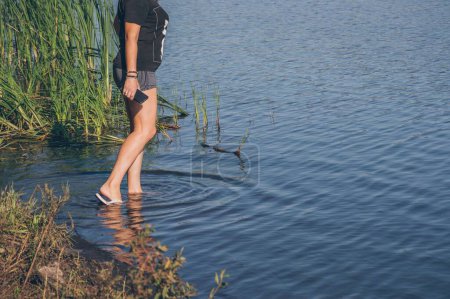 Foto de Las piernas de la muchacha en los shorts que entran en el río, los círculos sobre el agua - Imagen libre de derechos