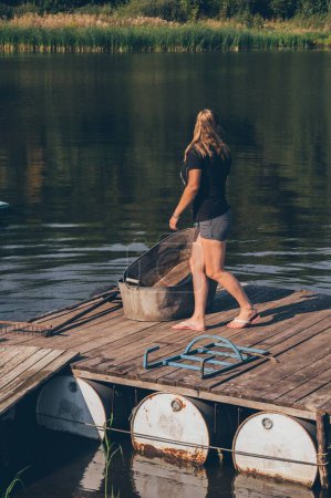 Téléchargez les photos : Femme marchant sur un vieux pont en bois, regardant en arrière sur l'eau - en image libre de droit