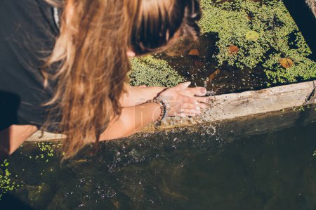 Téléchargez les photos : Femme se rince les pieds dans l'eau de la rivière à la lumière du soleil - en image libre de droit