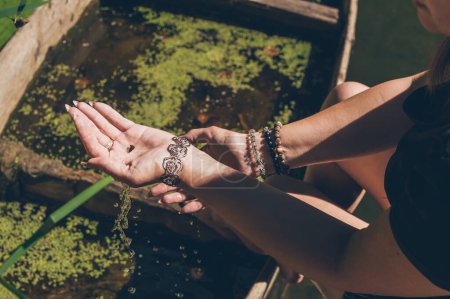 Foto de Pequeño caracol en manos de mujer con pulseras a la luz del sol - Imagen libre de derechos