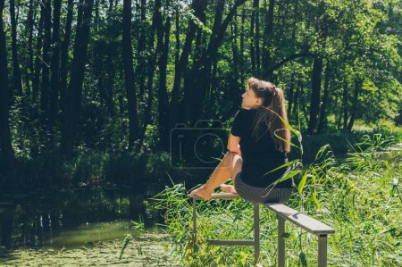 Téléchargez les photos : Femme assise et profitant du soleil et du paysage forestier - en image libre de droit