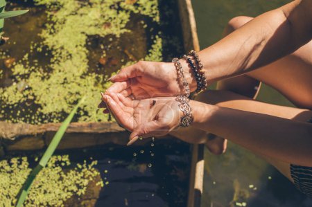 Foto de Pequeño caracol en manos de mujer con pulseras a la luz del sol - Imagen libre de derechos