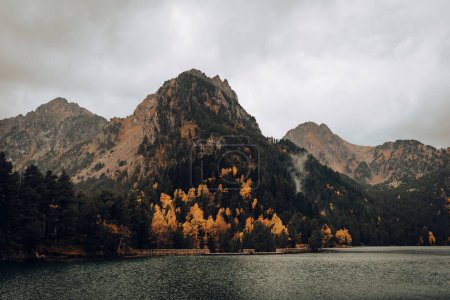 Foto de Montaña junto a un lago y algunos árboles durante un día nublado - Imagen libre de derechos