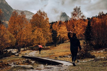 Foto de Chica caminando en un valle rodeado de montañas y árboles - Imagen libre de derechos