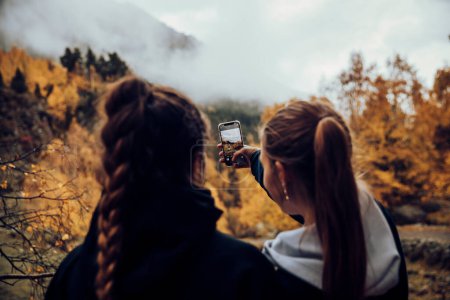 Foto de Amigos tomando una selfie con el móvil en las montañas en otoño - Imagen libre de derechos