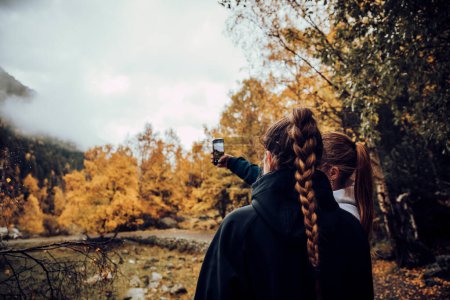 Téléchargez les photos : Amis prendre un selfie avec le mobile dans les montagnes en automne - en image libre de droit