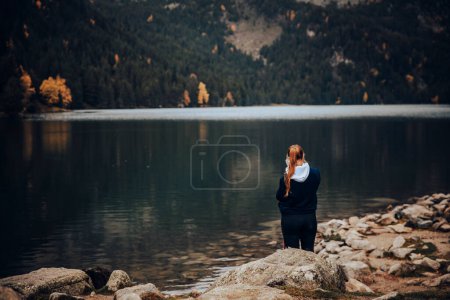 Foto de Chica de detrás de tomar fotos con su teléfono inteligente en un hermoso lago - Imagen libre de derechos