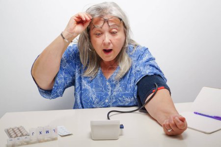 Photo for Woman with a surprised expression while taking a blood pressure test - Royalty Free Image