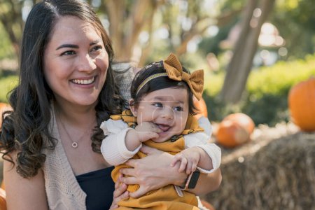 Téléchargez les photos : Brunette bébé fille et maman souriant à la ferme avec des citrouilles derrière - en image libre de droit