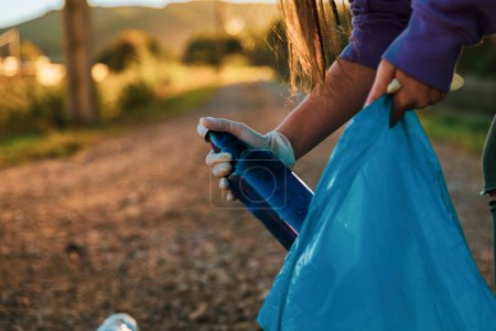 Photo for Girl recycling garbage in nature with gloves and a plastic bag - Royalty Free Image