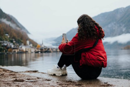 Foto de Mujer sentada junto al lago el pueblo de hallstatt - Imagen libre de derechos