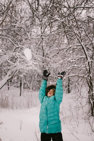 Photo for Child plays in snow covered forest in teal winter coat - Royalty Free Image
