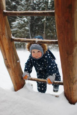 Téléchargez les photos : Garçon monter des escaliers en bois en hiver - en image libre de droit