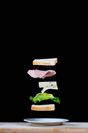 Téléchargez les photos : Un sandwich flottant au fromage, jambon cuit, laitue et pain tranché - en image libre de droit