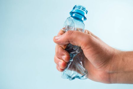 Foto de Pelar a mano una botella de plástico sobre fondo azul - Imagen libre de derechos