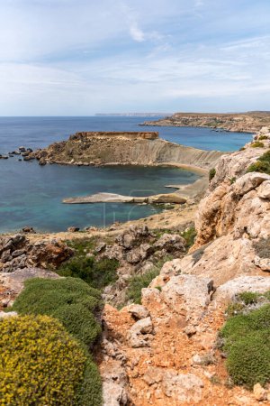 Téléchargez les photos : Mgarr, Malte Panorama de la baie de Gnejna, la plus belle plage de Malte au coucher du soleil avec un beau ciel coloré et des rochers dorés pris de Ta Lippija - en image libre de droit