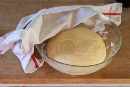 Photo for Homemade yeast dough covered with cotton towel in a glass bowl - Royalty Free Image