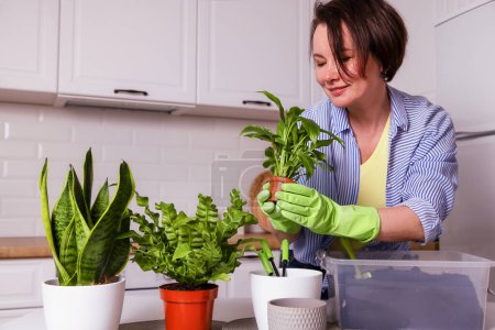 Téléchargez les photos : Femme heureuse faisant plantes à la maison à la maison - en image libre de droit