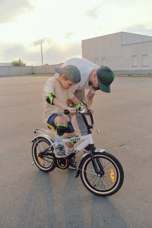 Photo for Father help his son ride a bicycle - Royalty Free Image