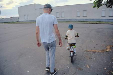 Téléchargez les photos : Père aider son fils à faire du vélo - en image libre de droit