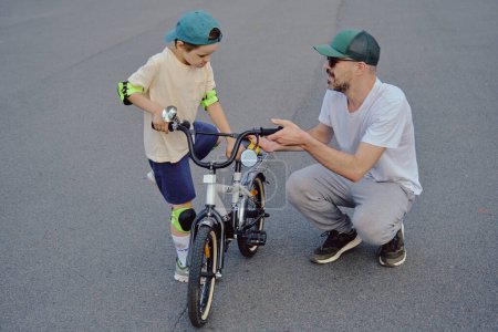 Foto de Padre ayuda a su hijo a montar en bicicleta - Imagen libre de derechos