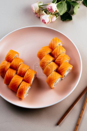 Téléchargez les photos : Deux types de sushis philXoa roulent sur une assiette et un fond coloré - en image libre de droit