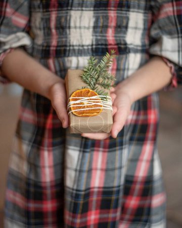 Photo for Girl holding present with orange slice and pine twig - Royalty Free Image