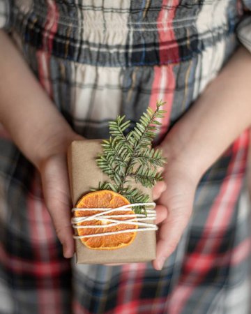 Photo for Girl holding present with orange slice and pine twig - Royalty Free Image