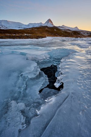Téléchargez les photos : Vue de dessus de la rivière gelée enneigée avec fente dans la glace en hiver au crépuscule - en image libre de droit