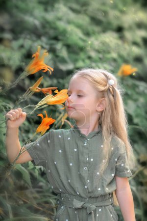 Foto de Niña sosteniendo una flor en sus manos y olerla - Imagen libre de derechos