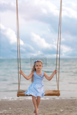 Photo for Girl riding a swing on the beach - Royalty Free Image