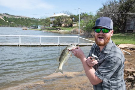 Photo for Happy man catching bass from the bank - Royalty Free Image