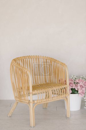 Foto de Silla de madera minimalista en casa blanca con flores en maceta junto a ella - Imagen libre de derechos