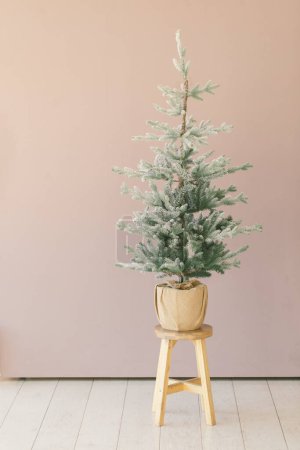 Photo for Small christmas tree sitting on top of stool in a minimal room - Royalty Free Image