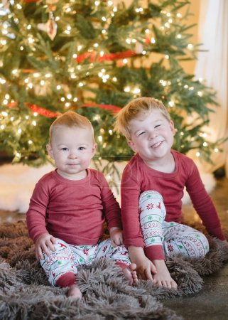 Photo for Boy and girl siblings in front of a glowing Christmas tree - Royalty Free Image