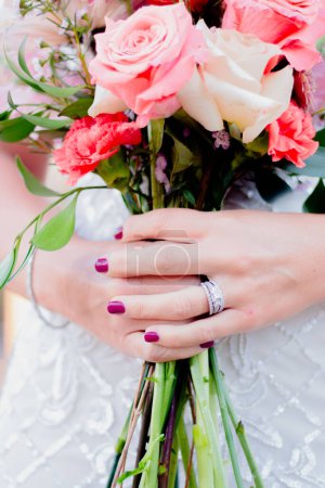 Foto de Manos de mujer sosteniendo ramo de flores. Ramo de boda de primavera con acentos de anillo - Imagen libre de derechos