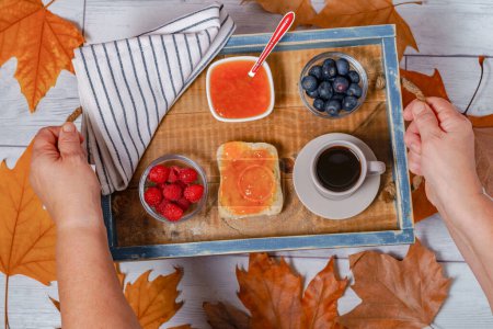 Photo for Woman holding a tray with healthy breakfast, berries, jam and coffee - Royalty Free Image