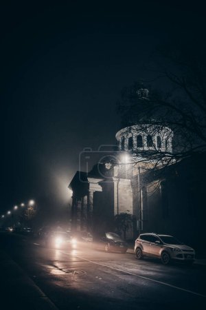 Photo for Car driving through a city street on a foggy autumn night. - Royalty Free Image