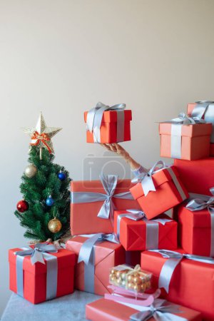 Photo for The hand of an unknown character is holding a gift in the air among other beautiful gifts - Royalty Free Image