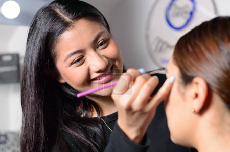 Téléchargez les photos : Maquilleur souriant maquillage pour femme - en image libre de droit