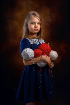 girl with balls of thread looking at the camera