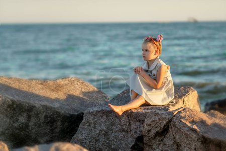 Photo for Girl sitting on the beach at sunset - Royalty Free Image