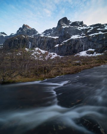 Foto de Los picos de montaña se elevan por encima del arroyo que fluye a principios de verano, Flakstady, Islas Lofoten, Noruega - Imagen libre de derechos